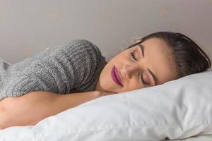 belle femme dormant sur un oreiller confortable dans son lit à la maison photo