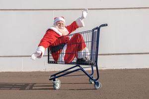 chariot de supermarché avec le père noël à l'intérieur. shopping pour le concept de noël. photo