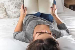 concept de loisirs et de personnes - jeune femme lisant un livre au lit photo