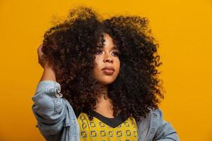 portrait de beauté d'une femme afro-américaine avec une coiffure afro et un maquillage glamour. femme brésilienne. race mixte. cheveux bouclés. coiffure. fond jaune. photo