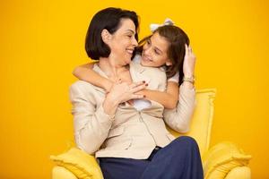 bonne fête des mères portrait en gros plan d'une jolie et charmante mère et fille avec des sourires rayonnants sur fond jaune. fille étreignant sa mère sur fond jaune. photo