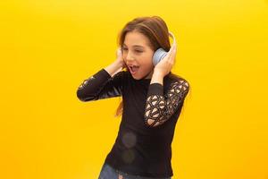 une petite fille mignonne appréciant l'écoute de la musique par casque isolé sur fond jaune. photo