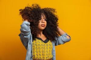 portrait de beauté d'une femme afro-américaine avec une coiffure afro et un maquillage glamour. femme brésilienne. race mixte. cheveux bouclés. coiffure. fond jaune. photo