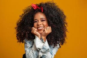portrait de beauté d'une femme afro-américaine avec une coiffure afro et un maquillage glamour. femme brésilienne. race mixte. cheveux bouclés. coiffure. fond jaune. photo