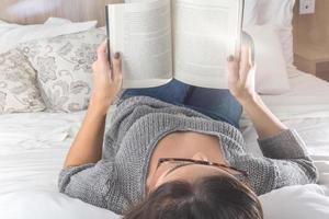 concept de loisirs et de personnes - jeune femme lisant un livre au lit photo