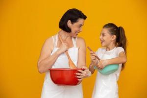notion de fête des mères. fille et mère préparant une recette sur fond jaune photo
