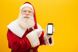 père noël avec téléphone portable sur fond jaune. concept de communication, compagnies de téléphone et promotions. photo