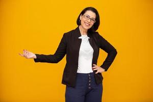 belle femme d'affaires d'âge moyen souriant et regardant la caméra pointant avec la main sur le côté. photo