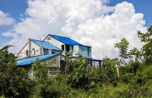 construire une maison abandonnée en béton bleu au milieu de la forêt dense pendant la journée.