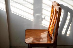 chaises en bois et la lumière du soleil à travers les fenêtres à volets sur les murs de la pièce. photo