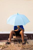 vue rapprochée d'un jeune garçon thaïlandais portant un t-shirt bleu tenant un parapluie bleu. photo