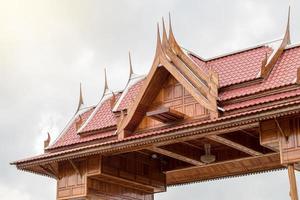 le toit d'une maison en bois thaïlandaise avec un ciel nuageux. photo