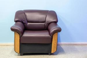 des fauteuils de canapé marron se tiennent seuls dans une pièce aux murs bleus.