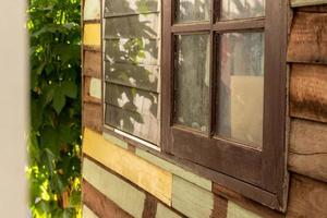 fenêtres latérales avec des murs en bois près des vieilles feuilles. photo