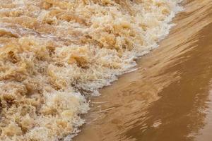 l'eau trouble brune se précipita sur le barrage débordant. photo