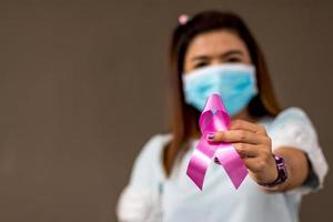 la femme de près porte un masque comme symbole contre le cancer du sein. photo