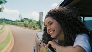 femme latine dans la fenêtre de la voiture. voyage en voiture. cheveux bouclés au vent. fille regarde par la fenêtre de la voiture. photo