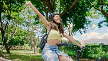 jeune femme latine en casque de protection fait du vélo le long de la piste cyclable dans un parc de la ville photo