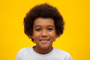 visage de garçon afro-américain avec des cheveux noirs sur fond jaune. enfant noir souriant avec des cheveux noirs. garçon noir avec des cheveux de puissance noirs. descendance africaine. photo