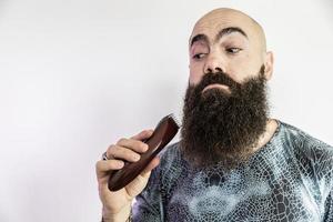 homme barbu va se raser la barbe avec un rasoir électronique photo