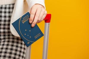 gros plan de la main d'une jeune fille titulaire d'un passeport brésilien. sur jaune. photo