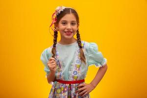 enfant en vêtements typiques de la célèbre fête brésilienne appelée festa junina en célébration de sao joao. belle fille sur fond jaune. photo