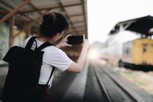 femme touristique aling selfie avec un smartphone à la gare. appréciant le concept de voyage. fille utilisant un smartphone sur le quai de la gare. photo