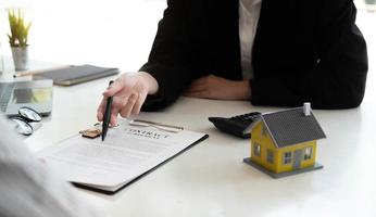 Les agents immobiliers sont expliquer aux clients qui signent un contrat d'achat d'une nouvelle maison. photo