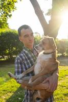 heureux jeune homme jouer avec un chien non de race dans le parc ensoleillé d'été photo