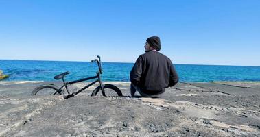 jeune homme avec planche à roulettes relaxant près de la mer photo