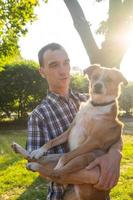 heureux jeune homme jouer avec un chien non de race dans le parc ensoleillé d'été photo