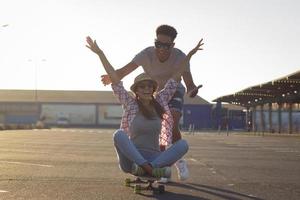 heureux jeune couple faisant de la planche à roulettes au lever du soleil photo