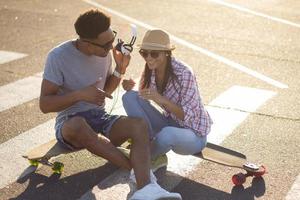 heureux jeune couple faisant de la planche à roulettes au lever du soleil photo