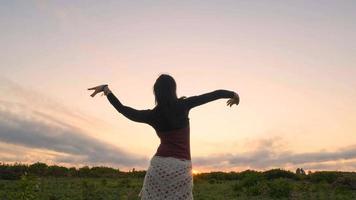 danse féminine heureuse dans les champs d'été pendant le beau coucher de soleil photo