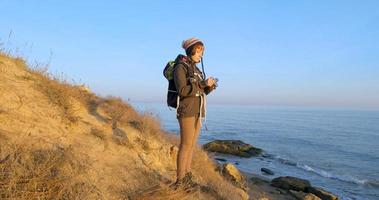 jeune femme travelr avec sac à dos et appareil photo argentique rétro voyage dans les montagnes d'automne près de la mer