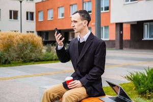 homme d'affaires travaille à l'extérieur avec un ordinateur portable et un téléphone portable photo