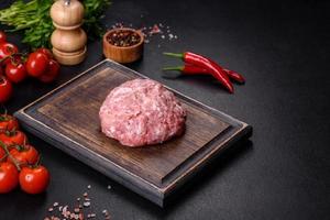 viande hachée avec des ingrédients pour la cuisson sur fond noir photo