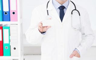 médecin à l'hôpital détient une carte de visite, assurance médicale, homme en uniforme blanc. copie espace photo