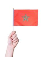 une main tient le drapeau le drapeau du maroc sur un fond blanc isolé. photo