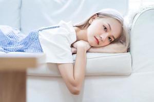 portrait de jeune fille asiatique allongée sur un canapé à la maison photo