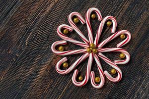 cannes de bonbon dans un dessin de fleurs avec des boules d'or scintillantes sur une table en bois rustique à plat photo