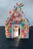 maison en pain d'épice construite par un enfant recouverte de bonbons colorés avec une lumière qui brille à travers la porte ouverte photo