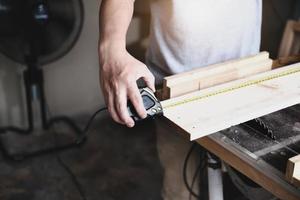 les artisans du concept de bricolage utilisent un ruban à mesurer pour assembler des pièces en bois afin de fabriquer des tables en bois pour les clients. photo