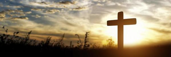 silhouette de croix catholique sur fond de coucher de soleil. image panoramique photo