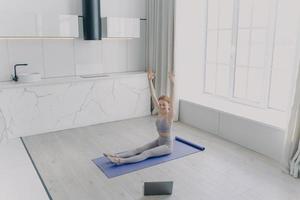 jeune femme enseigne le yoga en vidéo avec un ordinateur portable. concept de travail à distance en quarantaine. photo