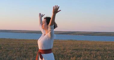 femme pratiquant le qigong dans les champs d'été avec un beau coucher de soleil sur fond photo