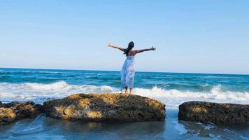 belle jeune femme vêtue d'une robe blanche marche pieds nus sur la plage d'été photo