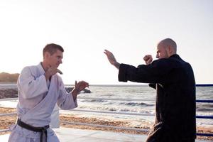 les combattants de karaté se battent sur le ring de boxe de la plage le matin photo