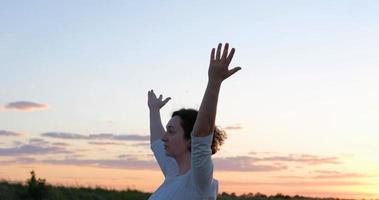 femme pratiquant le qigong dans les champs d'été avec un beau coucher de soleil sur fond photo