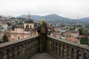 une voyageuse se tient sur le balcon du château avec vue sur la vieille ville de l'euro et les montagnes photo